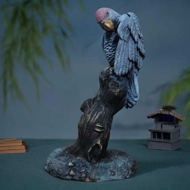 This elegant brass figurine features a highly detailed gray parrot perched upon a sculpted wooden branch. The bird is...