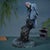 This elegant brass figurine features a highly detailed gray parrot perched upon a sculpted wooden branch. The bird is...