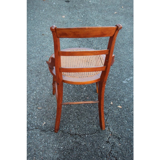 Vintage French Country cane seat chair. The wooden chair features a ladder back with arching side rails, and turned...