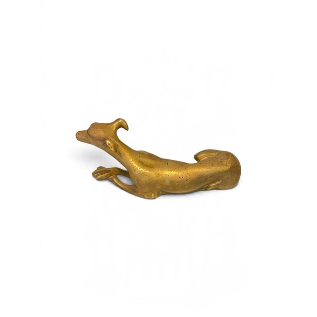 This striking mid-century modern cast brass sculpture depicts a sleek, reclining greyhound (lévrier) in a beautifully...