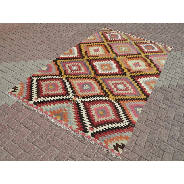 This Turkish Kilim rug hosts an intriguing pallet of vibrant rich and pastel colorways complementing a very turkish sense...