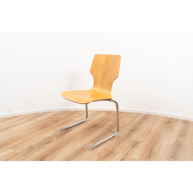 Vintage cantilever chair. The chair comes with a wooden backpiece and seating on a chrome plated metal frame.