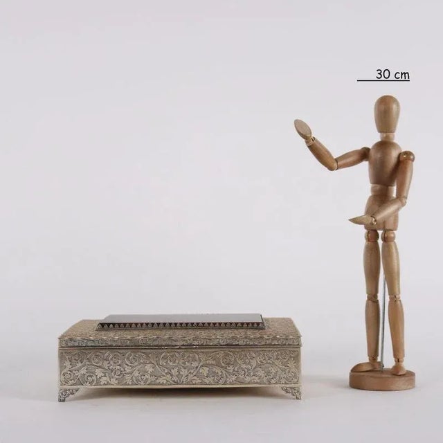 Embossed silver box engraved with leaf scrolls supported by four feet. On the lid with wavy edge, setting of an agate-like...