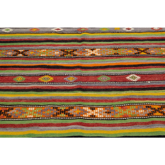 Beautiful Vintage Kilim hand-knotted wool rug with a multicolor accents in an all-over geometric stripe design. This rug...
