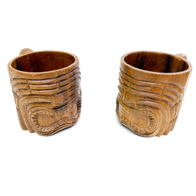 A striking pair of hand-carved wooden tiki mugs, exuding that perfect 1960s–1970s tropical lounge energy. Each mug...