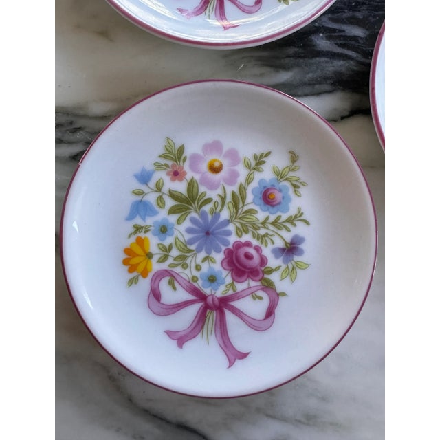Here is a darling vintage set of four miniature 3.75" plates featuring a spring and summer floral nosegay tied with a pink...