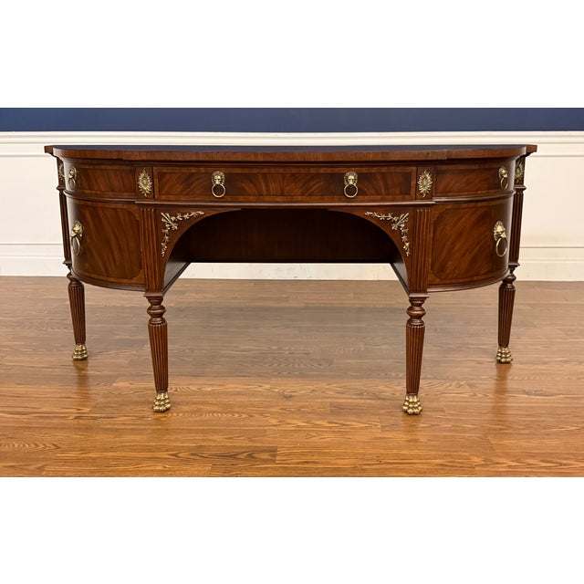 This is the Lillian Sideboard by Maitland - Smith. It has traditional styling with a curved front, Brass Lion pulls and...