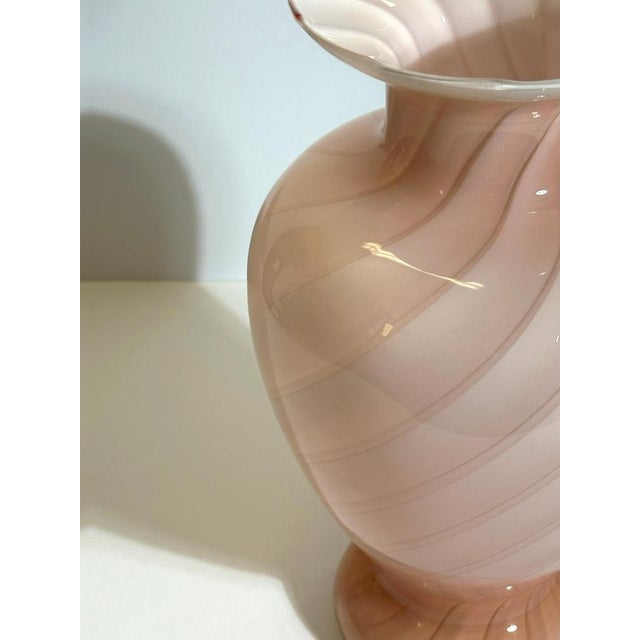 This Murano pink cased glass vase, produced in Italy in the 1970s, is a finely executed example of vintage Murano glass...