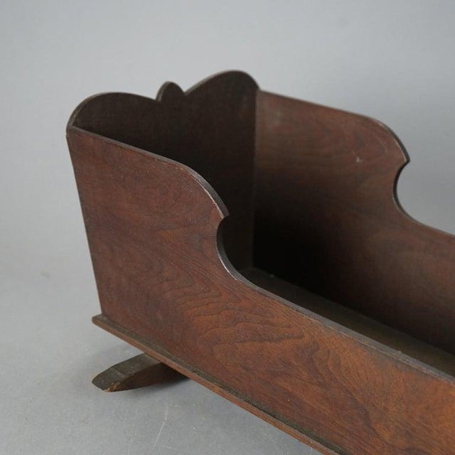 A walnut doll cradle showcases the simplicity and craftsmanship typical of the mid-19th century. The cradle features a...
