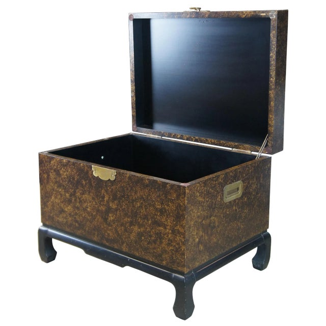 Late 20th century Chinese trunk on stand. Made from hardwood with a mottled gold finish and black lacquer Ming style base....