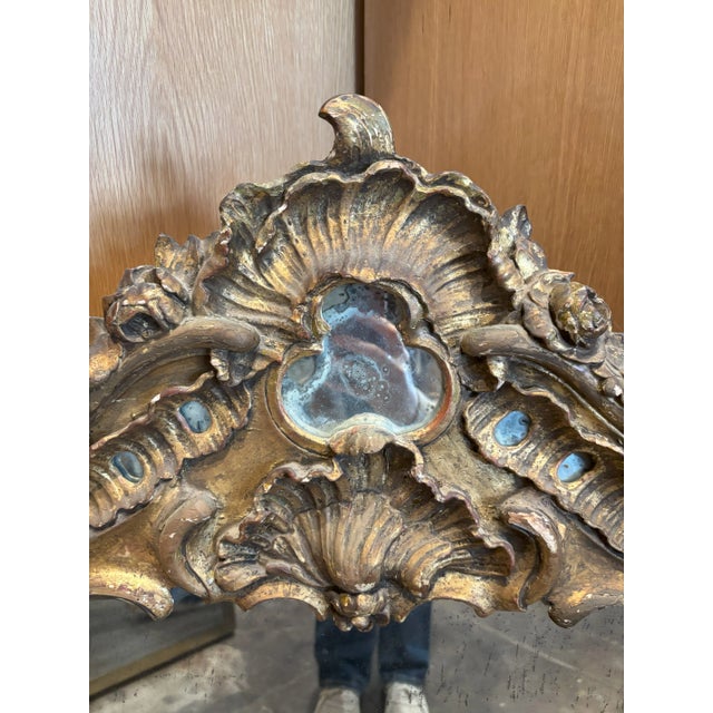 Antique carved giltwood mirror with very rich and boisterous frame carved in floral motifs with medallion like crown on...