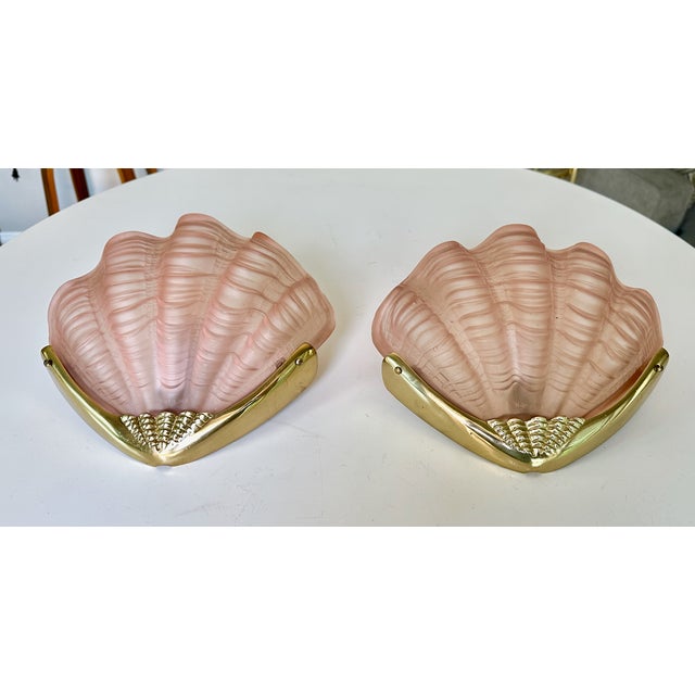 Pair of Deco clam shell shaped pink frosted glass shades with brass seashell motif backplates wall sconces. Each takes one...