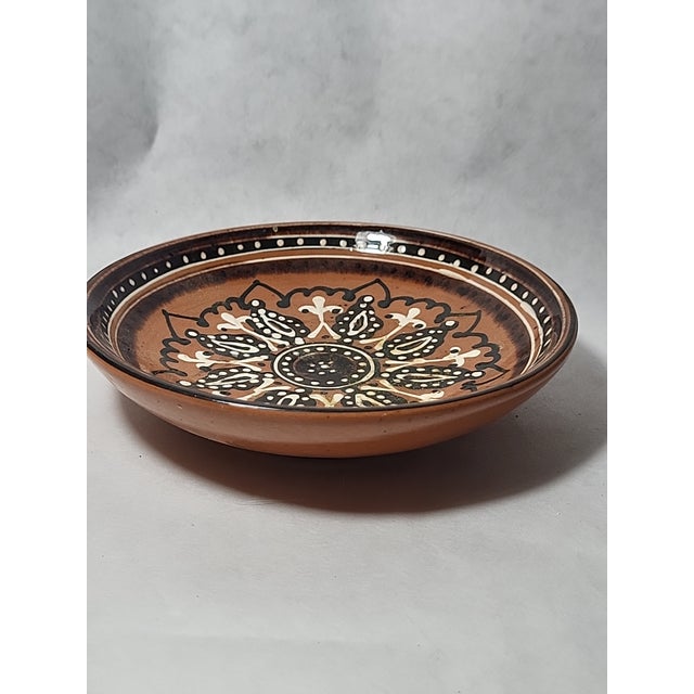 This Troyan Bulgarian redware pottery decorative plate is a fine example of traditional Balkan craftsmanship, renowned for...