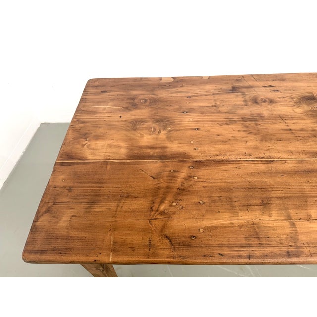 Solid pine farmhouse table with tapered legs, made in france in the 1950s. The three-plank pine top boasts a deep and...