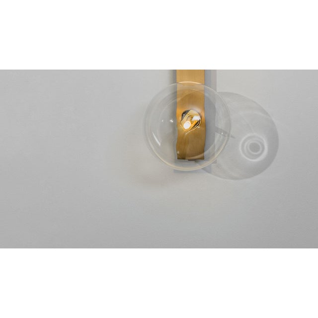 Glass bubbles alight upon a slender rectangle of brass for an essential design. Inspired by the sober compositions of...