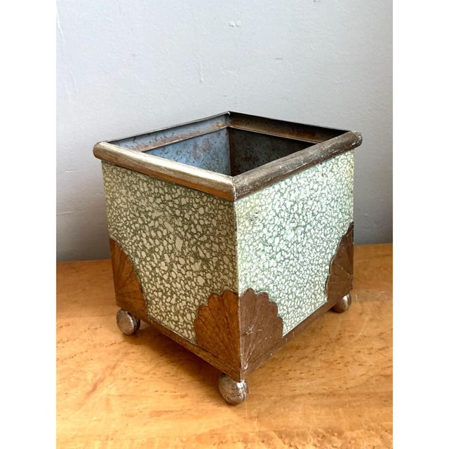 This vintage painted metal cache pot pairs a soft pale green finish with charming shell motifs, a combination that brings...