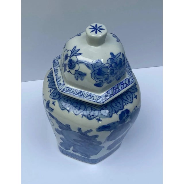 Hexagon shape ginger jar with varying hand painted blue fruit, flora and border designs on white ground. The dome top lid...