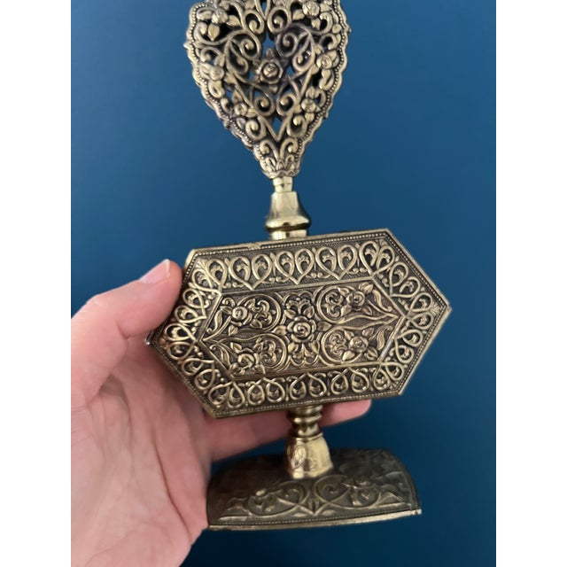 This rare vintage perfume bottle features an intricate brass body with floral filigree details and a pierced heart-shaped...