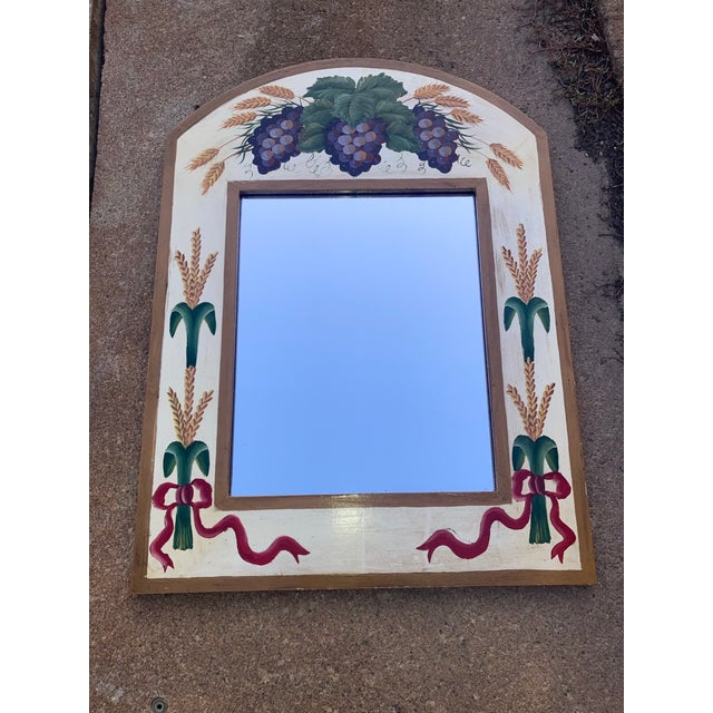 Mirror is framed beautifully with hand painted wheat bundles with flowing red ribbons. Top of mirror features purple grape...