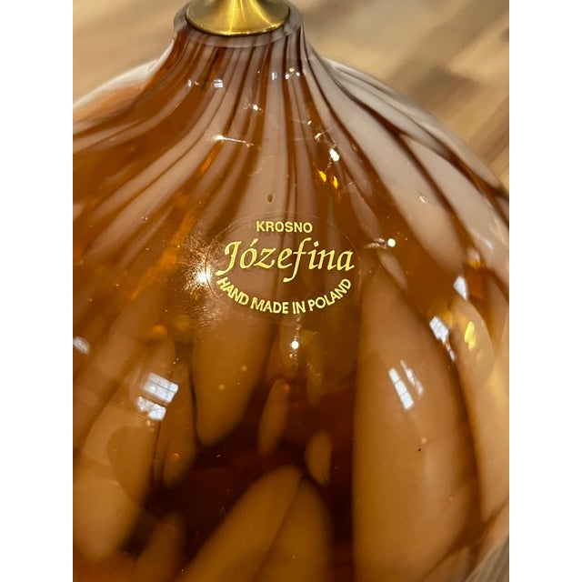 This is a Józefina handmade glass oil lamp in an amber and white swirl design.Brand: Józefina. Material: Hand-blown glass....