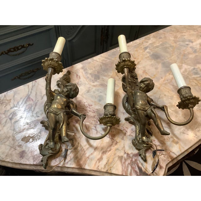 These antique cherub wall sconces are a striking blend of French Rococo elegance and classical European design. Crafted in...