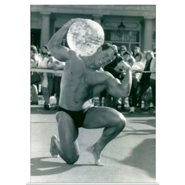 1986 Swedish black and white photo of a body builder striking an Atlas pose with a globe.