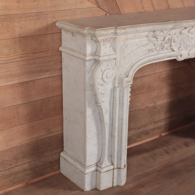A substantial Rococo style antique fireplace in Italian White marble. A finely carved frieze with ornate medallion inside...