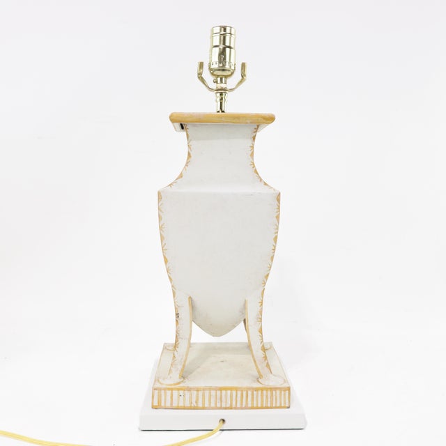 This vintage table lamp features a striking hand-painted coat of arms motif, framed by detailed laurel wreaths. The urn-...