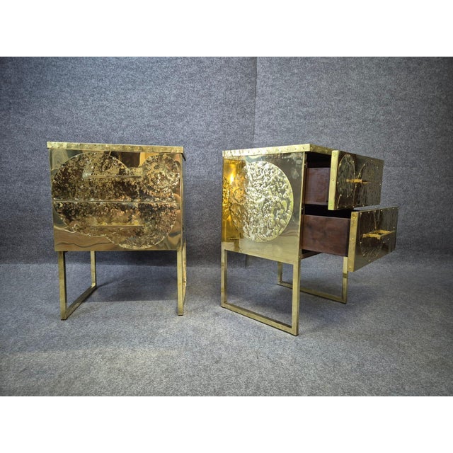 Pair of brass nightstands with a black opaline top and two drawers. The sides and front are decorated with circular...