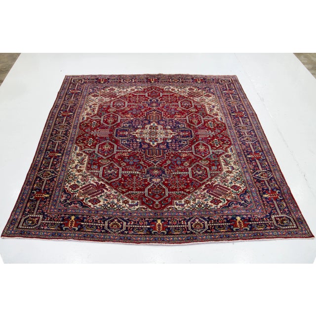 Vintage Heriz Handmade Persian Wool rug with an allover multicolor Motif in a red background. This rug measures 10'1" x 13'.