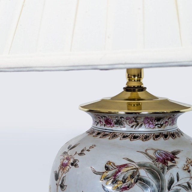 This table lamp features a ceramic base with a detailed floral pattern in soft colors. It includes a classic cream-colored...