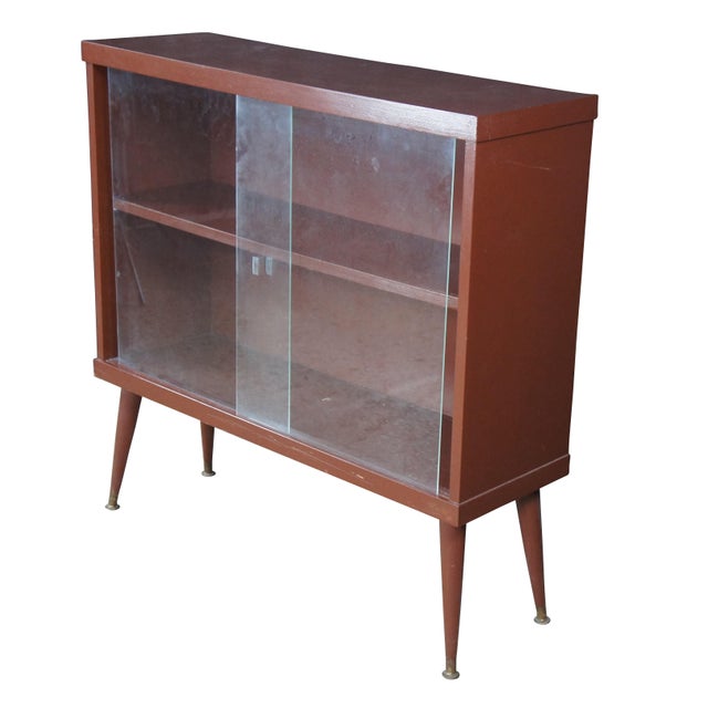 Mid century book case / curio cabinet with sliding glass doors, two shelves, and tapered legs. Dimensions: 35" x 35" x 11.5"