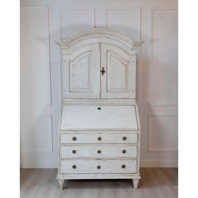 A distinguished Swedish writing cupboard crafted in solid pine, dating to approximately 1800. The two-part form combines...