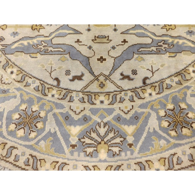 Ivory field within light blue round border. Wool pile on cotton foundation. Hand knotted in India. 10'x 10'.