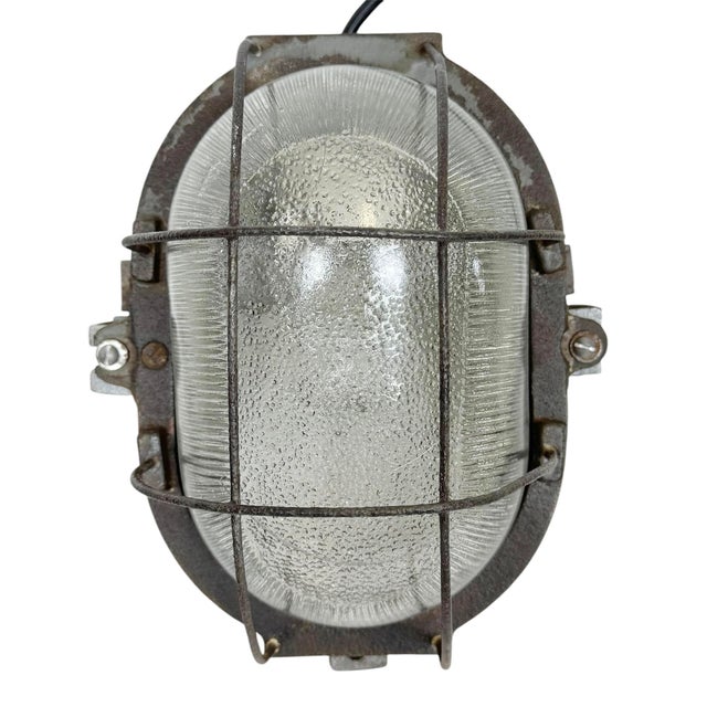 Vintage Industrial wall light made in Poland during the 1960s. It features a cast iron body ,an iron grig and a clear...