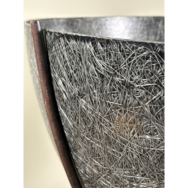 This mid century planter by Kimball, features a sculptural iron tripod base supporting a dark gray textured fiberglass...