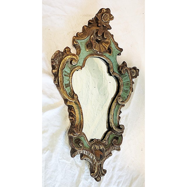 A classic Italian rococo style wall mirror in a small package. Shield shaped solid gesso, gilt and painted with a crest, c...