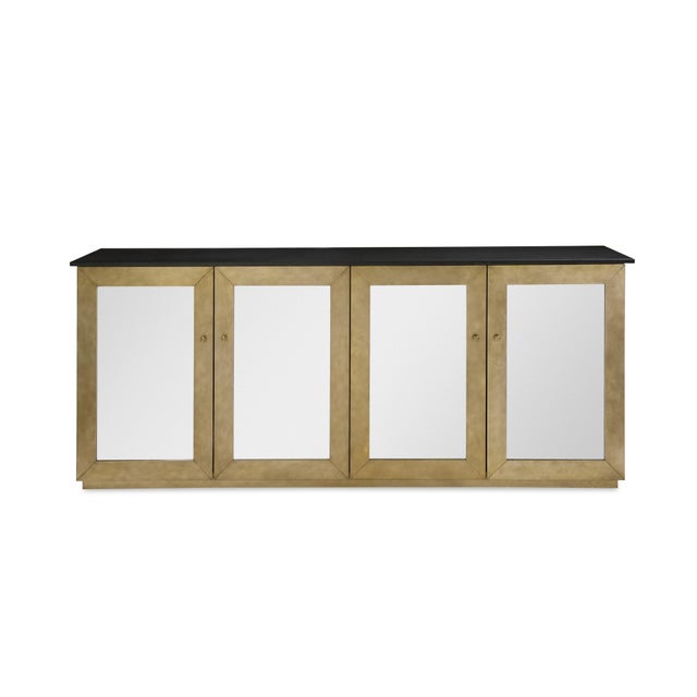 The brass four-door credenza with a honed marble top, inspired by mid-century design, reflects the mid-20th century's...