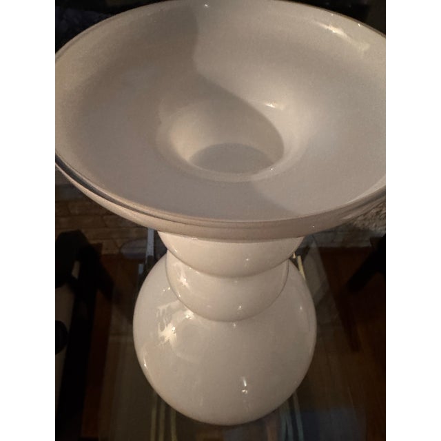 A striking sculptural floor vase in luminous opaque white glass. Its dramatic rounded body, stacked forms, and flared...