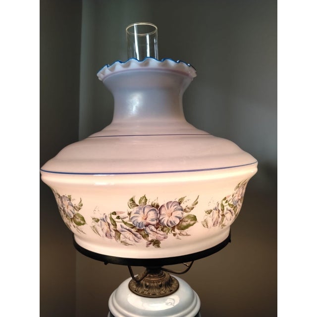 This lamp from the 1960s features a bronze frame and two glass shades—one sky-blue and white—adorned with blue flowers and...