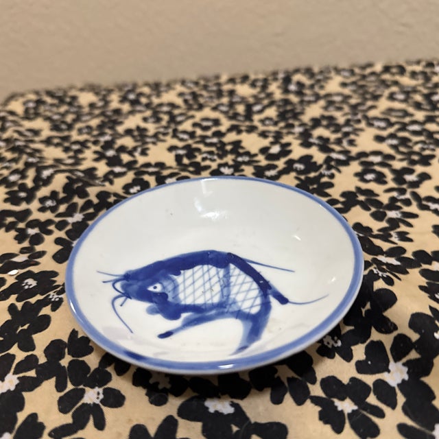 This charming, small ceramic dish features a classic hand-painted koi carp design in a deep cobalt blue against a crisp...