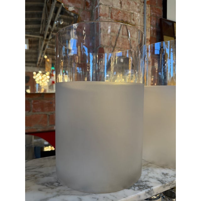 A pair of elegant frosted glass cylinder lamps featuring a minimalist, modern design. Each piece showcases a smooth...