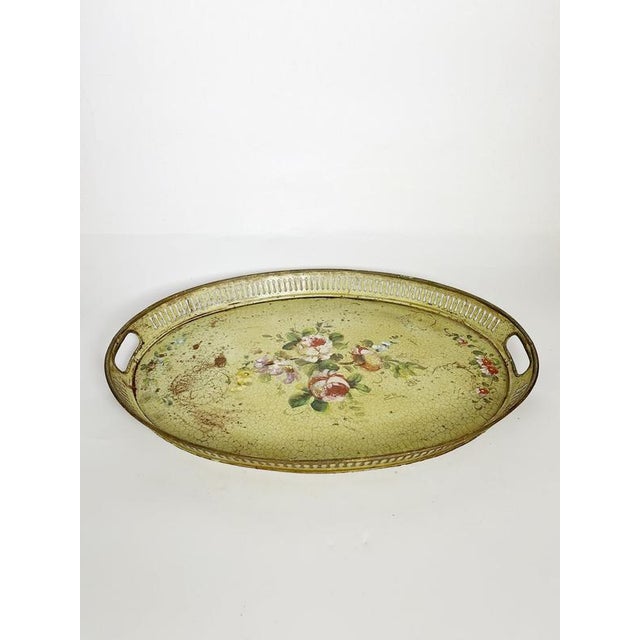 A charming metal serving tray featuring a hand-painted floral design set against a light green background with a crackle...