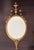 Elegant antique giltwood mirror in the Louis XVI taste, featuring a refined oval form crowned with a classical urn finial...
