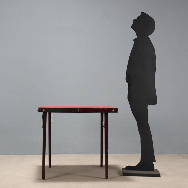 Folding table in stained beech wood, top covered in cloth fabric. This piece is attributed to the mentioned...