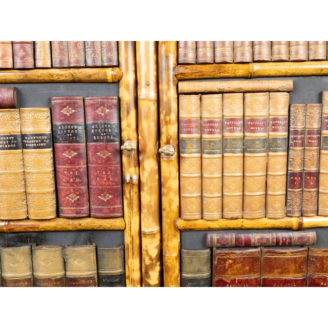 An English bamboo cabinet from the early 20th century, with faux books façade. Created in England during the early years...