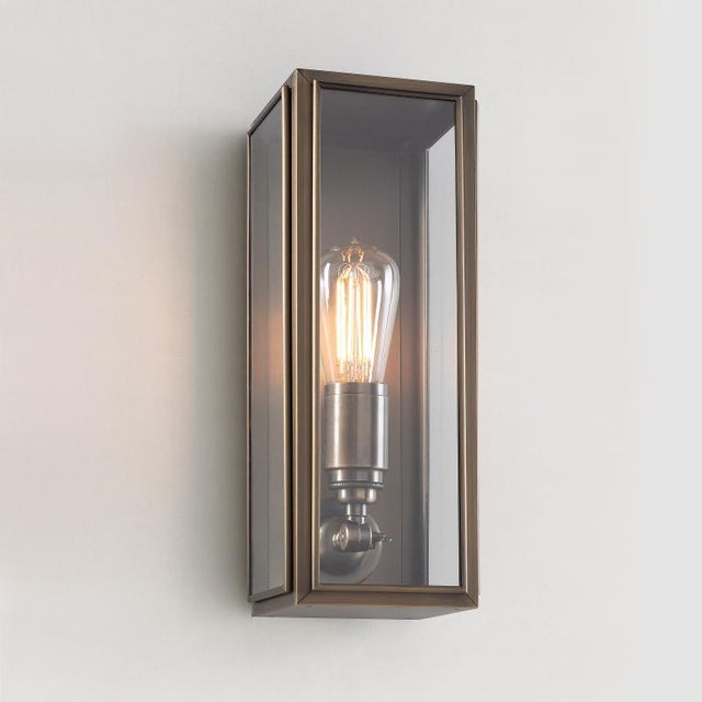 Wall light in brass with outside fitted clear glass. Spring closure. Gauze: (removable) woven metal gauze at the inside of...