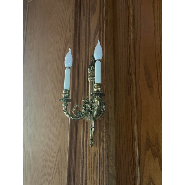 Set of 11 ornate French Neoclassical-style solid brass two-light wall sconces. Scrolling foliate arms with candle-style...