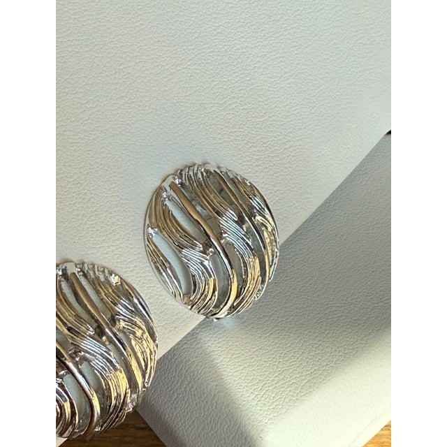 Vintage Silvertone round button clip on earrings by Kramer. Bands of textured swirl and polish in modern late 20th century...