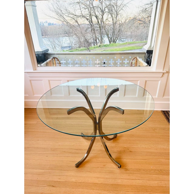 Sleek chrome and glass Mid-Century Modern Italian-style dining table circa the 1960's. Heavy glass sits atop pedestal...